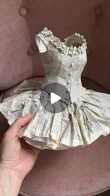 someone is holding up a dress made out of old book pages that have been turned into an origami doll