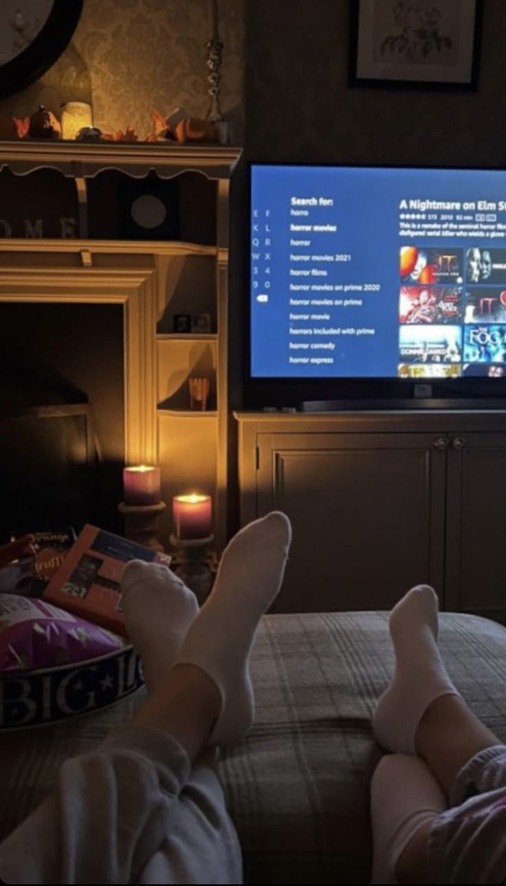 someone is watching tv in the dark with their feet propped up on the bed,