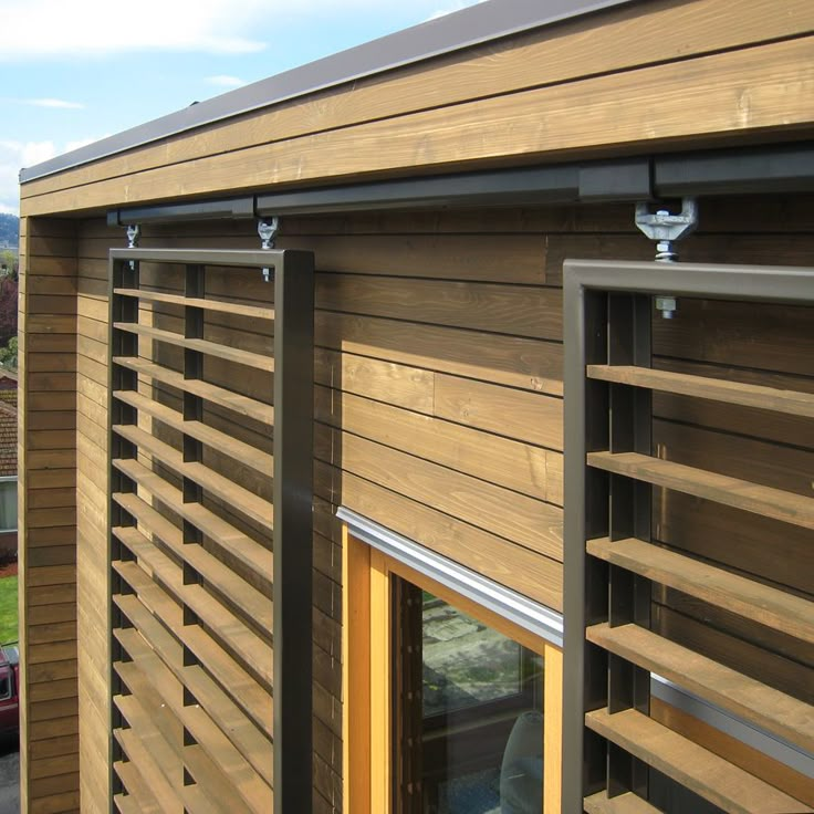 the side of a wooden building with shutters open