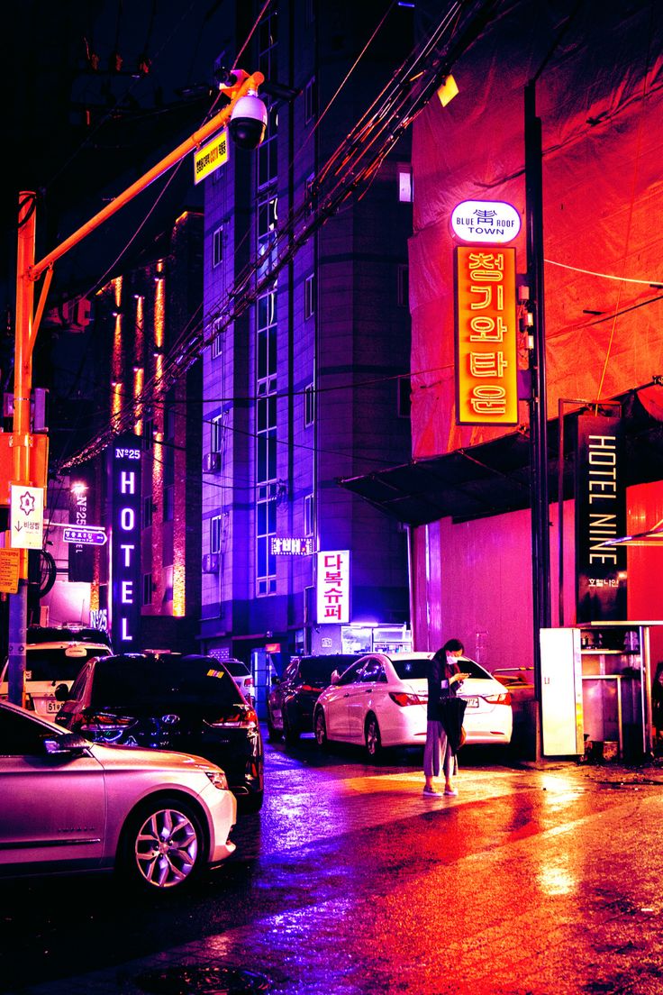 a city street at night with cars parked on the side