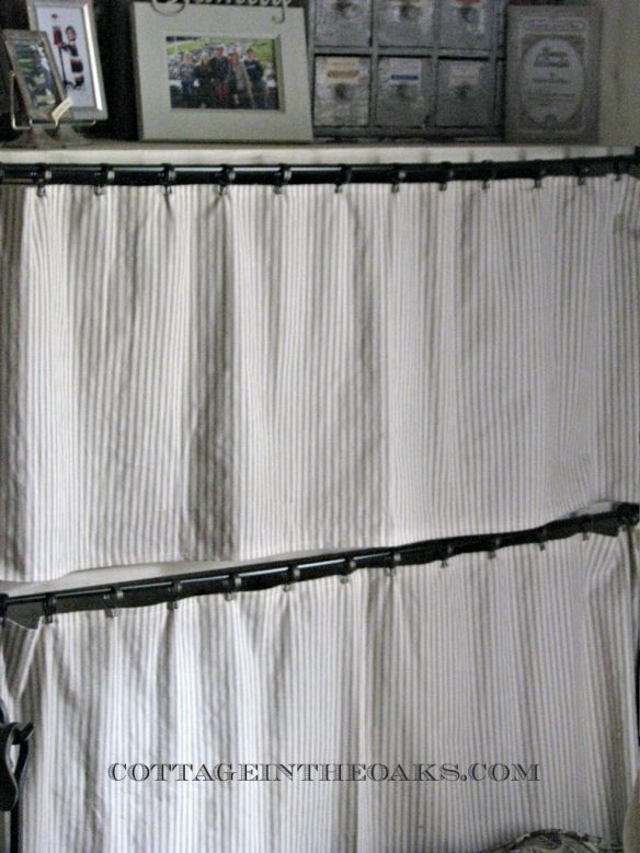 a white curtain hanging from the side of a wall next to a bed with pictures on it