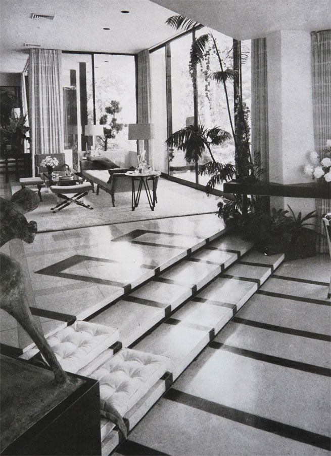 a black and white photo of a living room filled with furniture