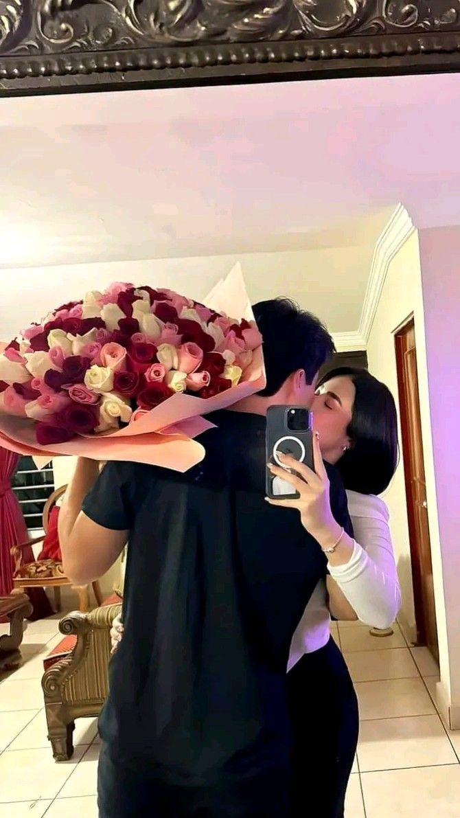 a man and woman taking a selfie in front of a mirror with flowers on it