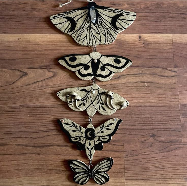 three butterflies are hanging on a wooden floor with chains attached to the back of them