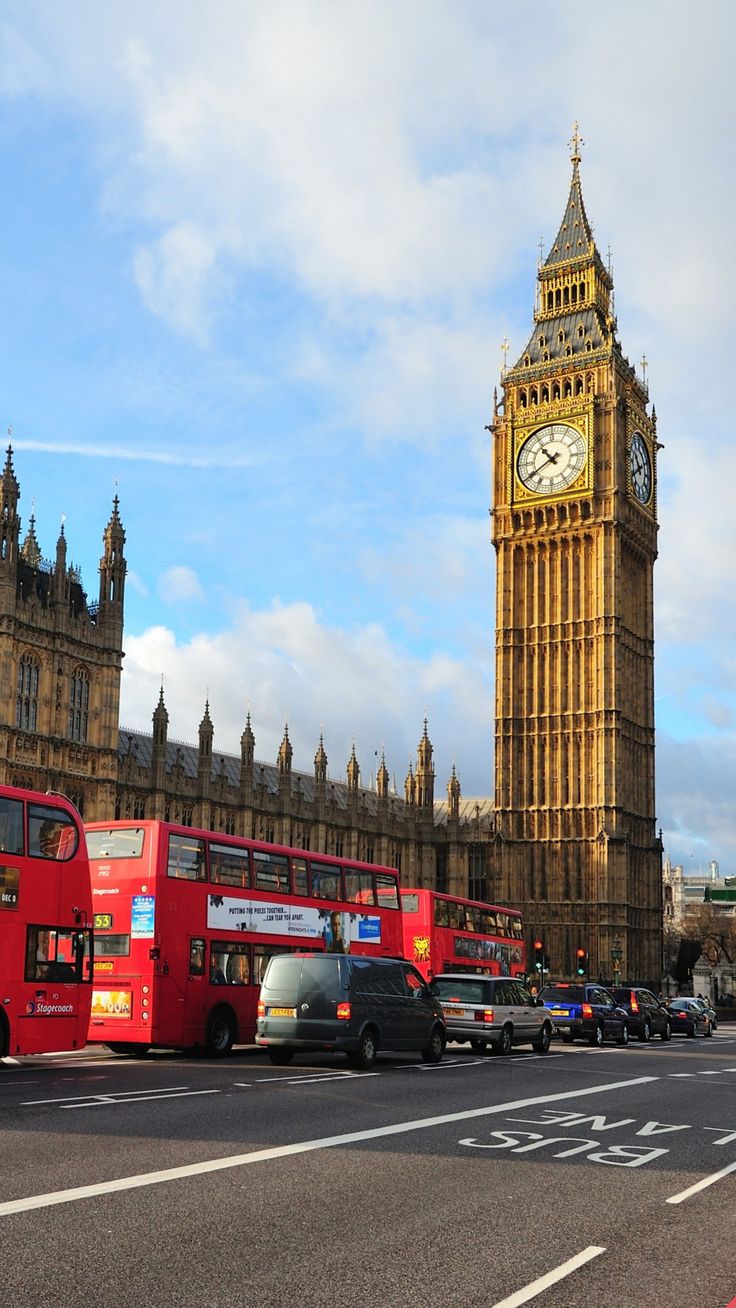 big ben towering over the city of london with red double decker buses parked in front