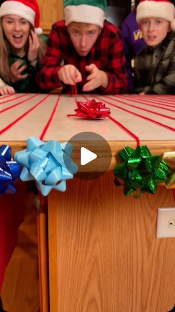 the kids are all wearing christmas hats and wrapping presents on the table with their hands