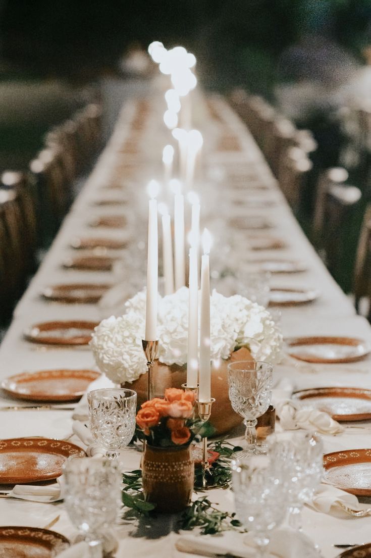 a long table is set with candles and flowers for an elegant dinner or party setting