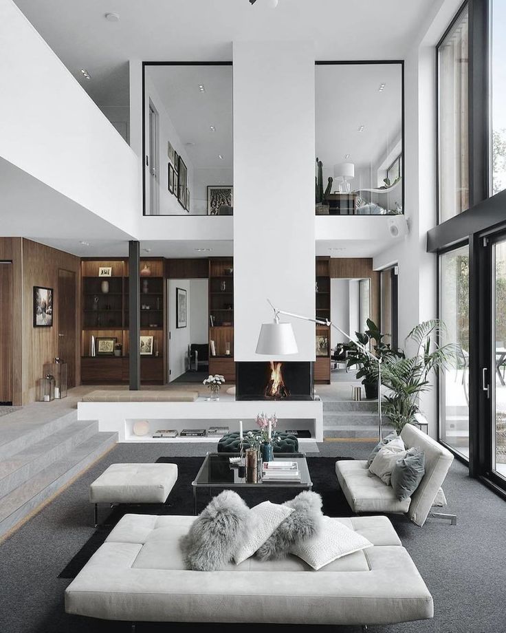 a living room with couches, tables and windows in the wall to the outside