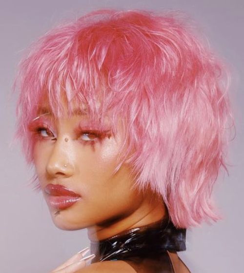 a woman with pink hair and black latex on her chest wearing a leather choker