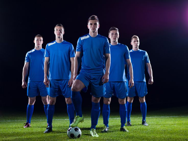 a group of young men standing next to each other on top of a soccer field