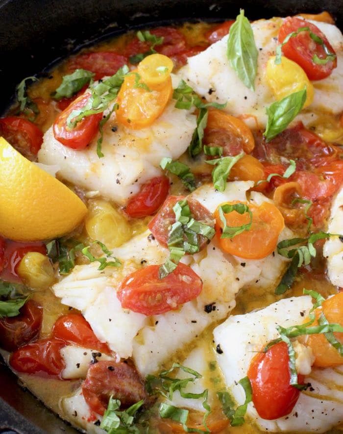 fish with tomatoes, lemon and herbs in a skillet