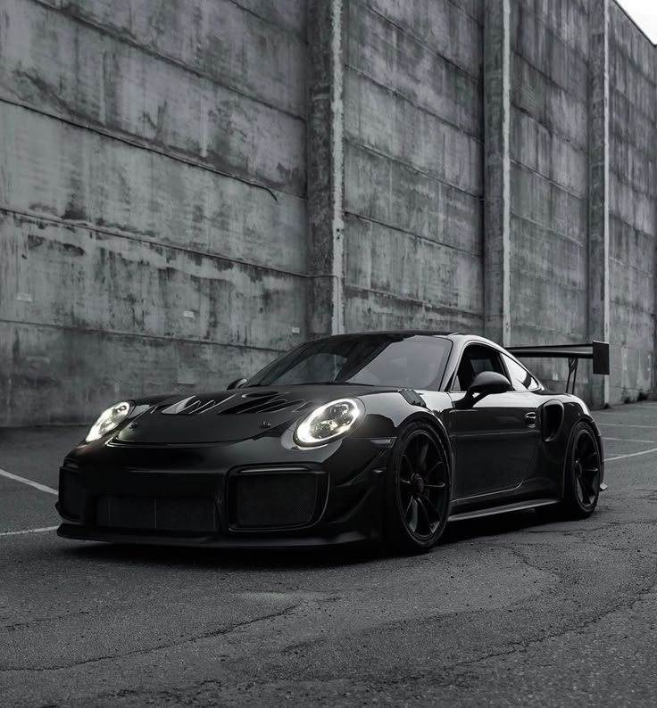 a black and white photo of a porsche gtr car parked in front of a building