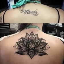 the back of a woman's neck with a lotus tattoo on her left shoulder