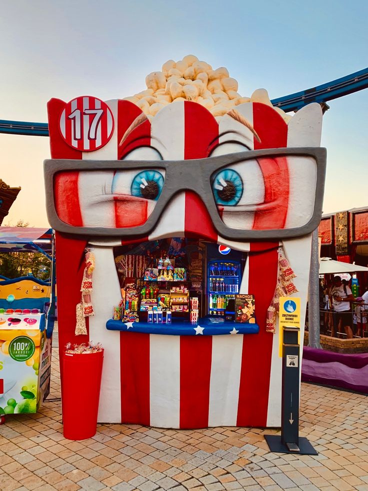 a giant popcorn machine with glasses on it's face and some food in front of it