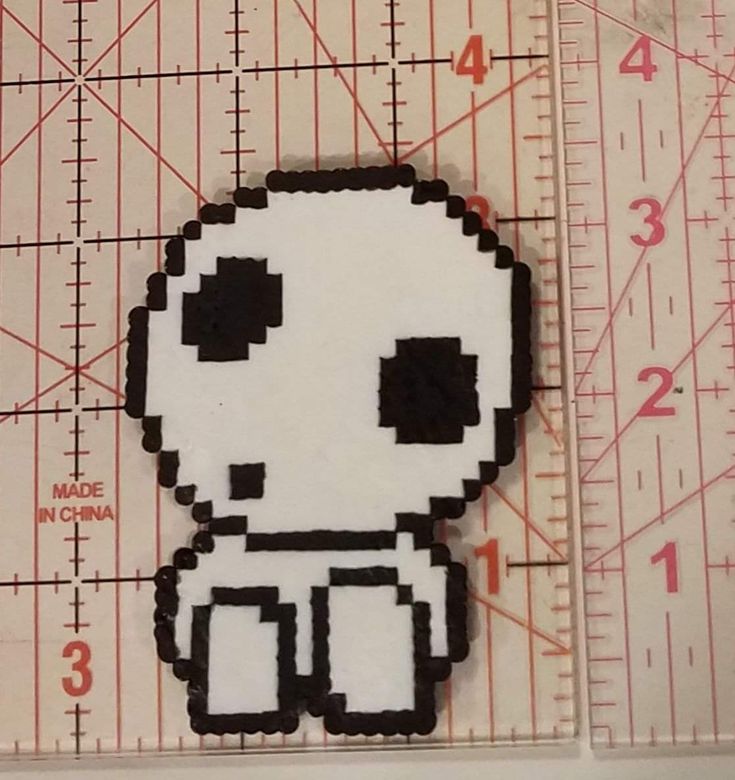 a close up of a piece of paper with a pixel art design on it, next to a ruler