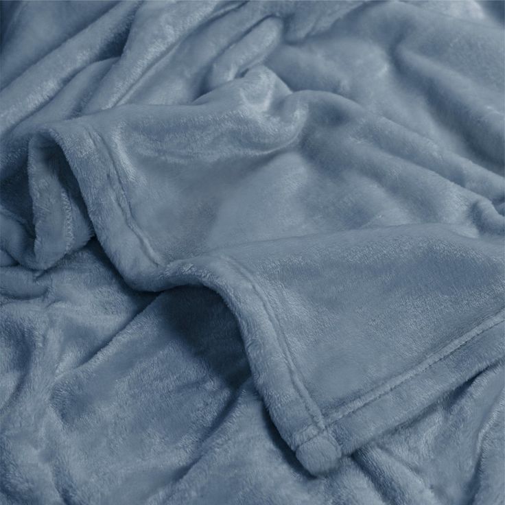 an unmade bed with blue sheets on top of it and a blanket folded over the edge