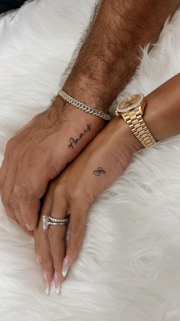 two people holding hands with tattoos on their fingers and wristbands that say love