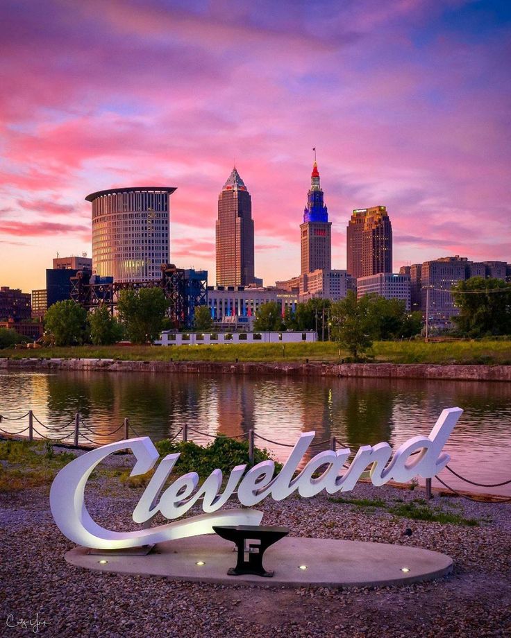 the cleveland sign is in front of a beautiful cityscape and river at sunset