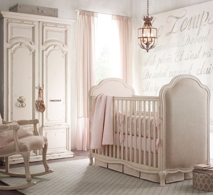 a baby's room with a crib, rocking chair and chandelier