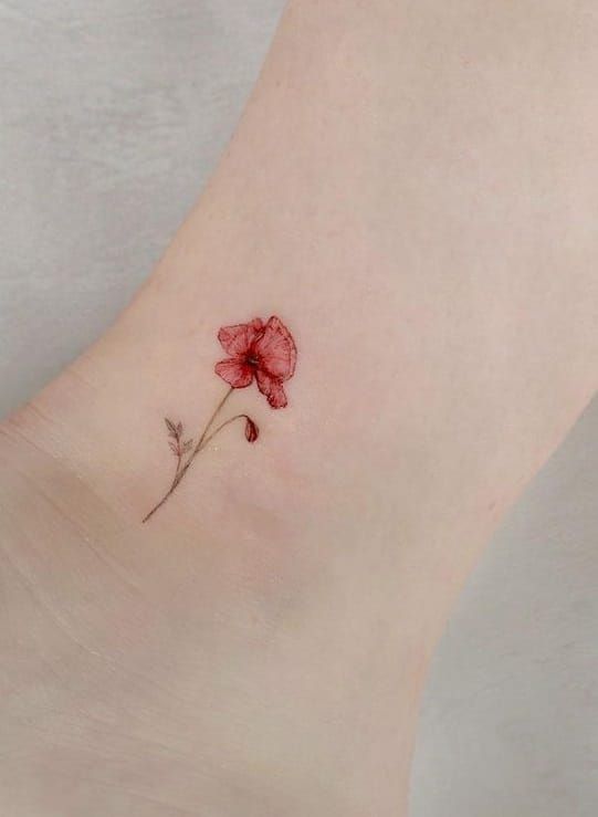 a small red flower on the ankle is shown in close up, it appears to have been inked