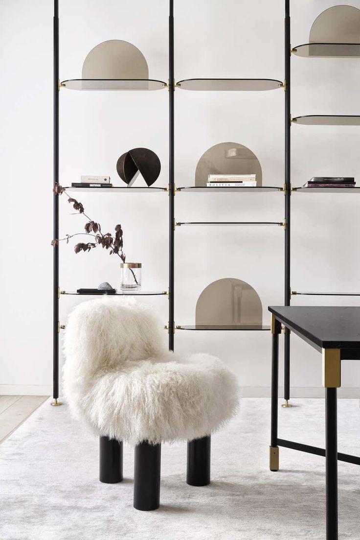 a white chair sitting on top of a rug next to a shelf filled with books