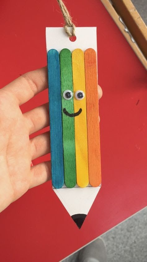 a hand holding a pencil shaped like a smiling face