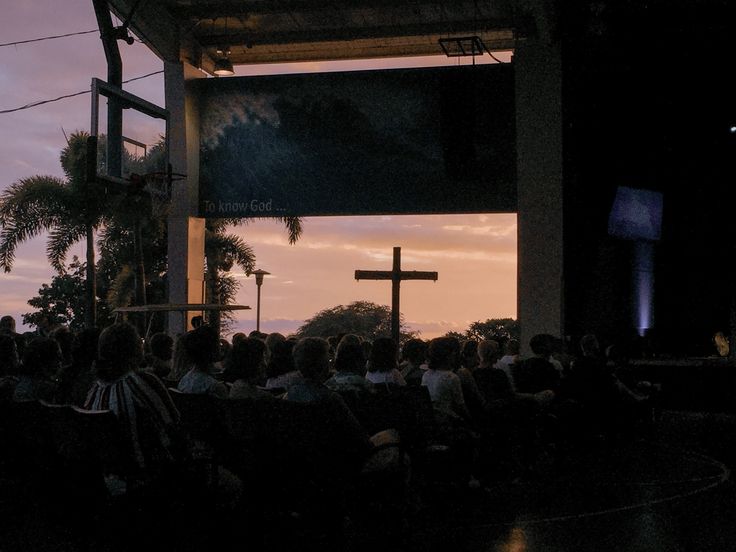 a group of people sitting in front of a cross