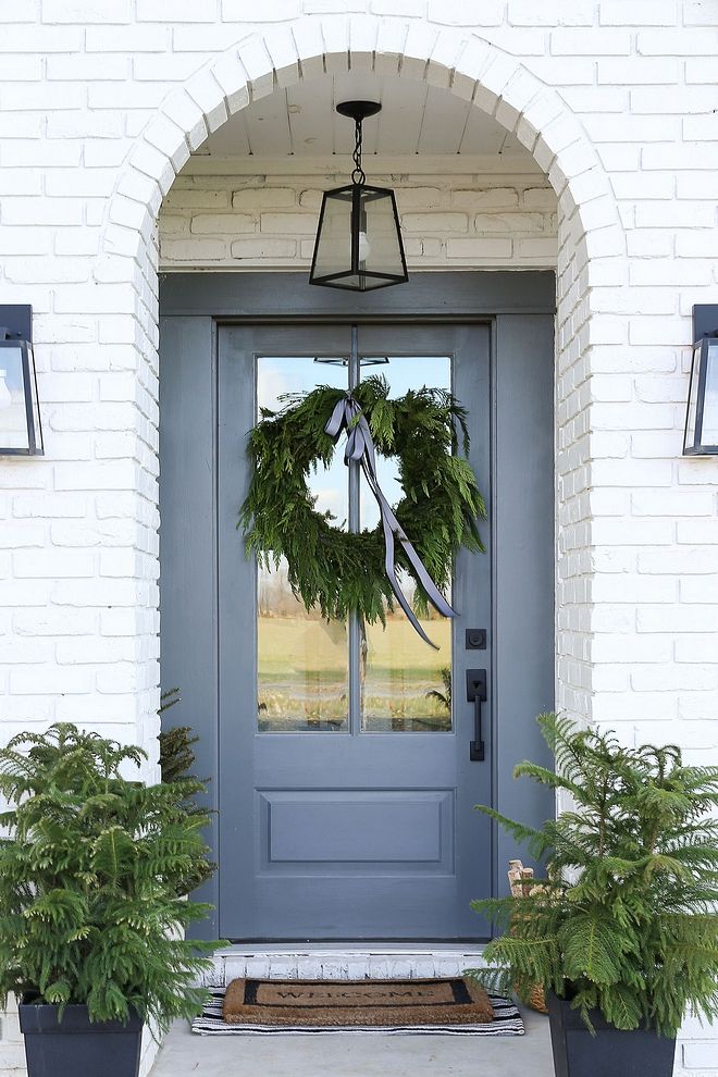 a blue front door with two planters and a wreath