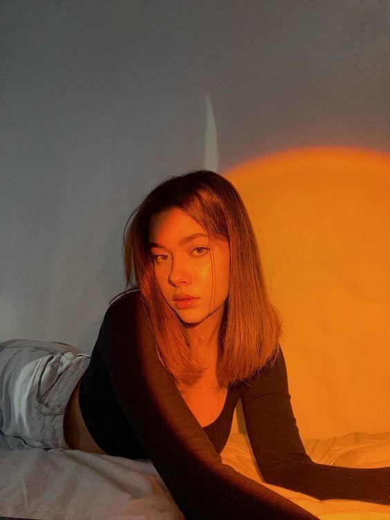 a woman laying on top of a bed next to a yellow light