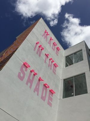 a tall white building with pink lettering on it's side and the words made in the shade