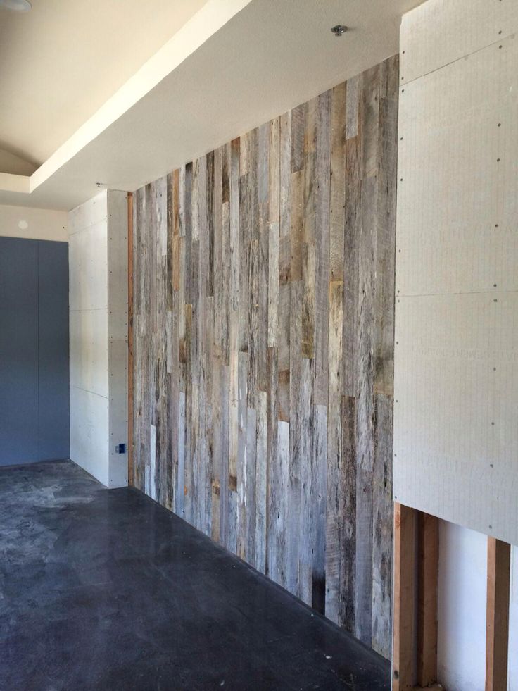 an empty room with wood paneling on the wall and concrete floor in front of it