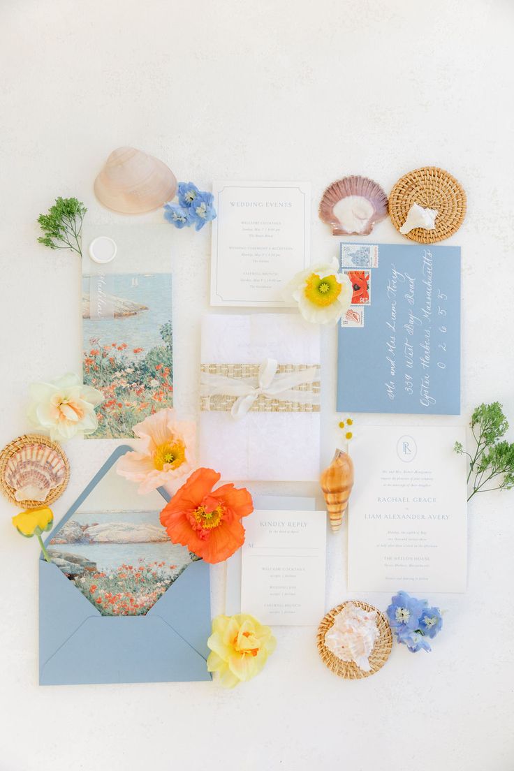 the wedding stationery is laid out on top of each other with flowers and seashells