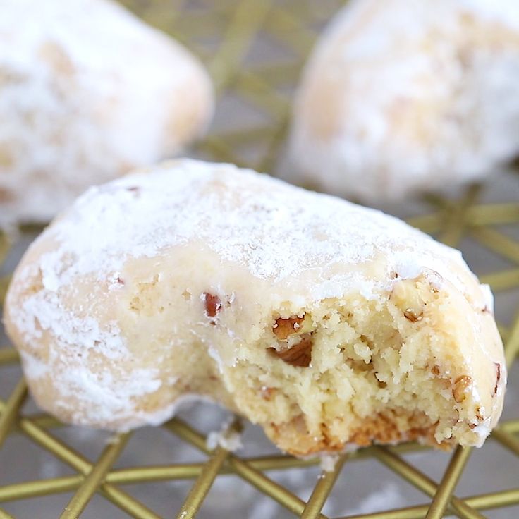 powdered sugar donuts on a cooling rack with one bite taken from the top