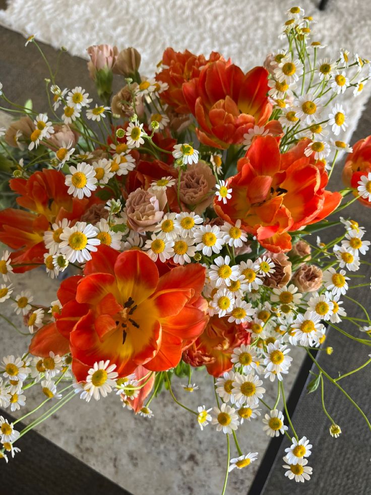 a vase filled with lots of orange and white flowers