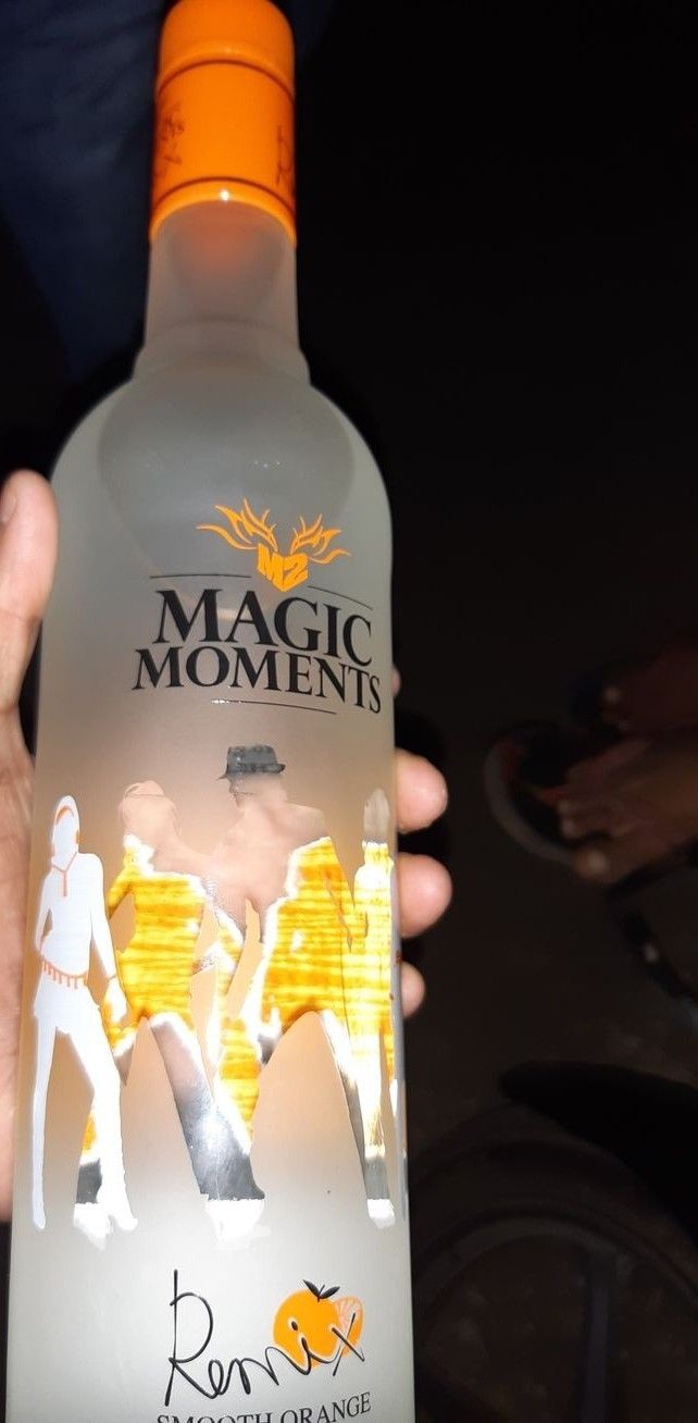 a person holding up a bottle of magic moments