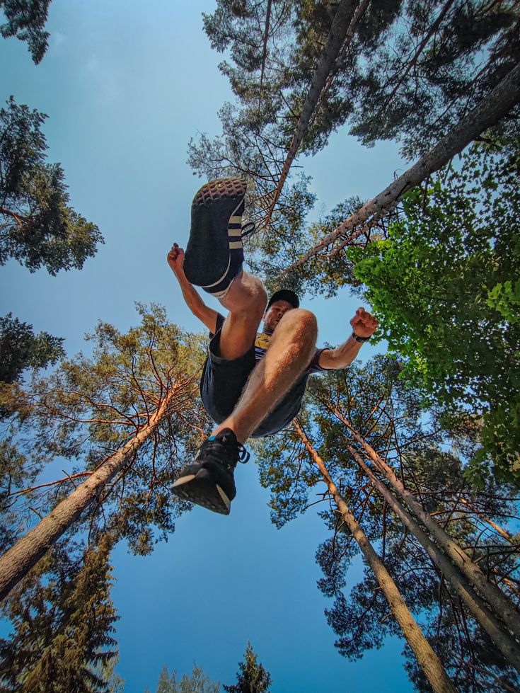 a man flying through the air while riding a skateboard in front of some trees