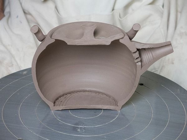 a clay pot sitting on top of a piece of pottery with holes in the middle