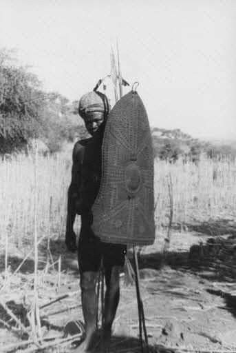 an old photo of a man carrying a large object in his back pack and wearing a helmet