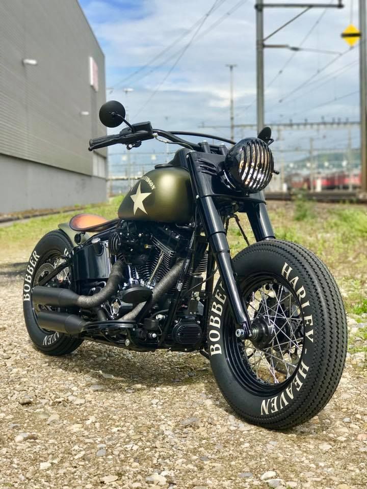 a black motorcycle parked on top of a dirt road next to a building and power lines