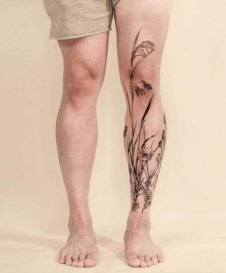 a man's legs with flowers and grass tattoo on the lower part of his leg