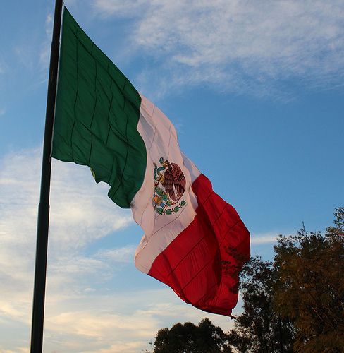 the mexican flag is flying high in the sky