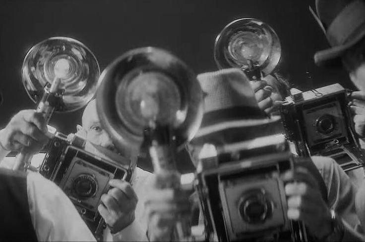 a group of men holding up some old cameras and looking at them with magnifying glasses on their faces