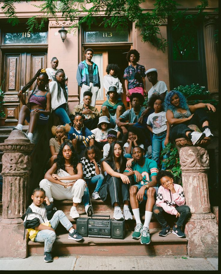 a group of people sitting and standing on steps in front of a building with trees