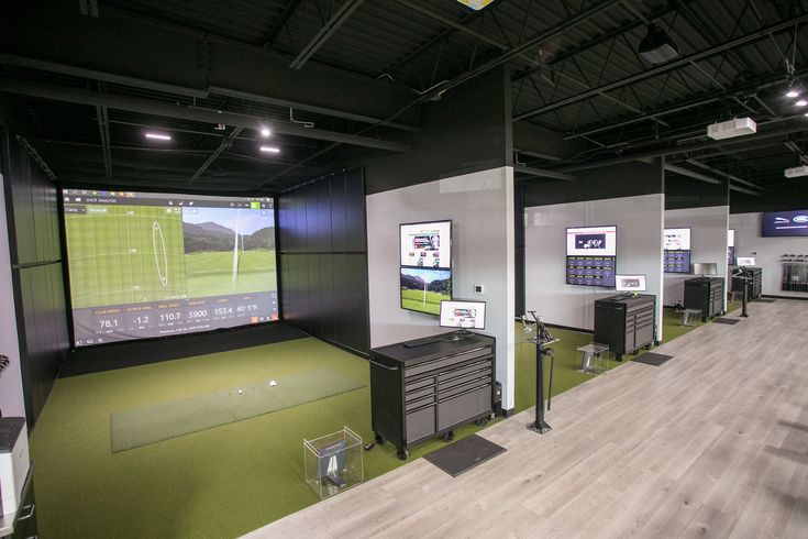 an indoor golf simulator is set up in a large room with lots of equipment on the walls