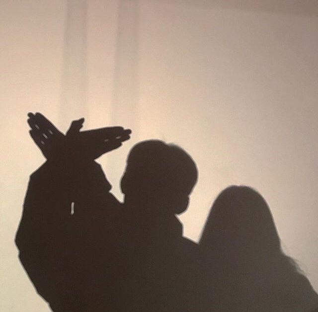 the shadow of a person holding a cell phone up in the air with their hands