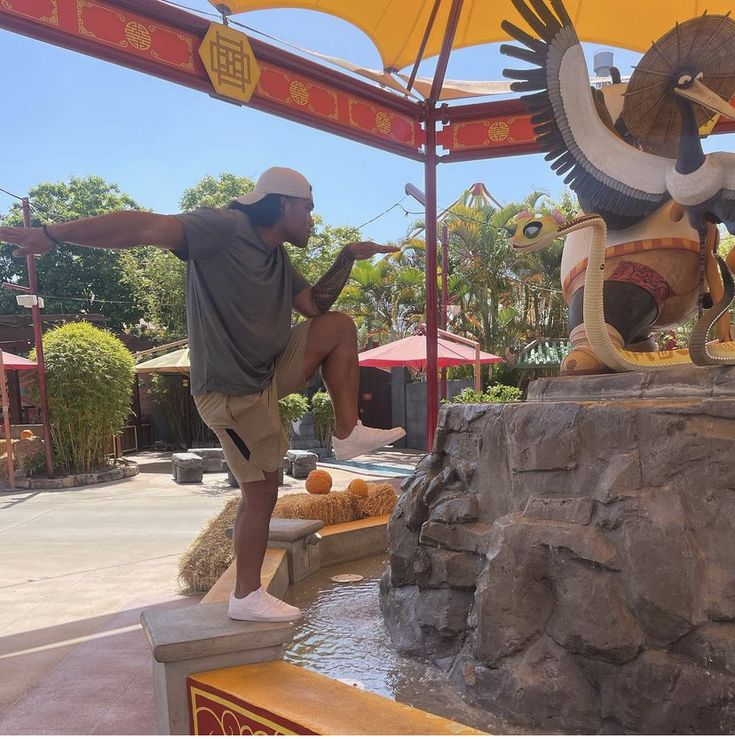 a man standing on top of a statue next to a fountain