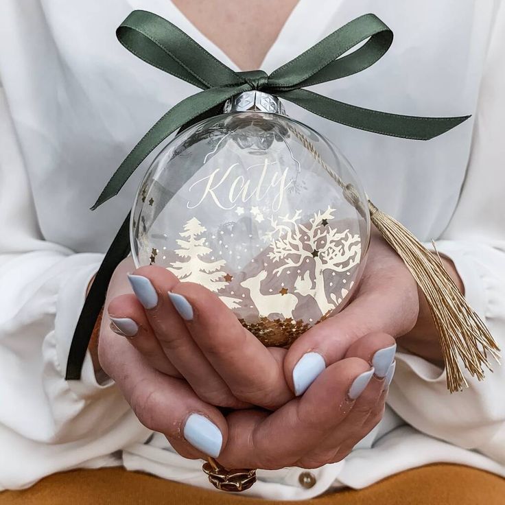 a woman holding a christmas ornament in her hands