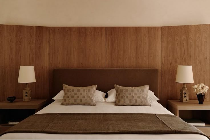 a bed with two nightstands and lamps on either side of the headboard in a bedroom