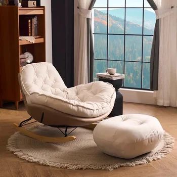 a white chair and ottoman in front of a large window with mountains out the side