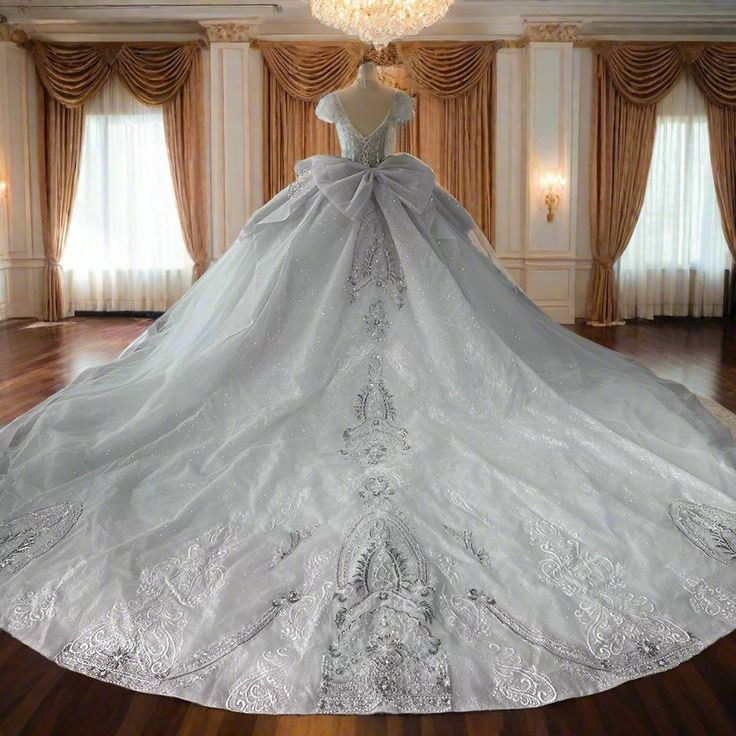 a white wedding dress is on display in a room with curtains and chandelier